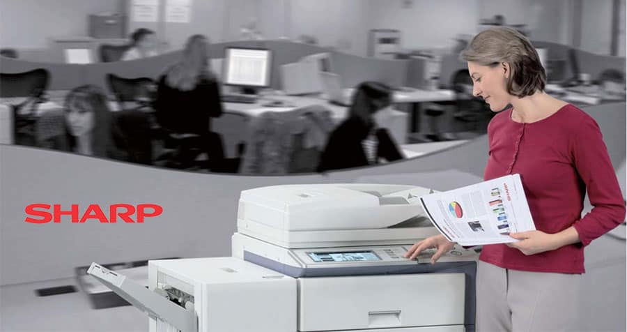 Woman stands at Sharp photocopier collecting prints
